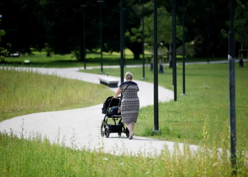 Sieviete ar bērnu ratiem Uzvaras parkā.