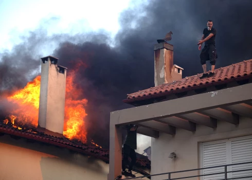 Local residents try to extinguish the fire of a burning house during a wildfire in Kryoneri, near Athens on July 26, 2025. Greece has already been hit by a series of heatwave-fuelled wildfires this summer, including one that forced the closure of the Acropolis in Athens, its top archaeological monument, earlier this month. (Photo by Angelos TZORTZINIS / AFP)