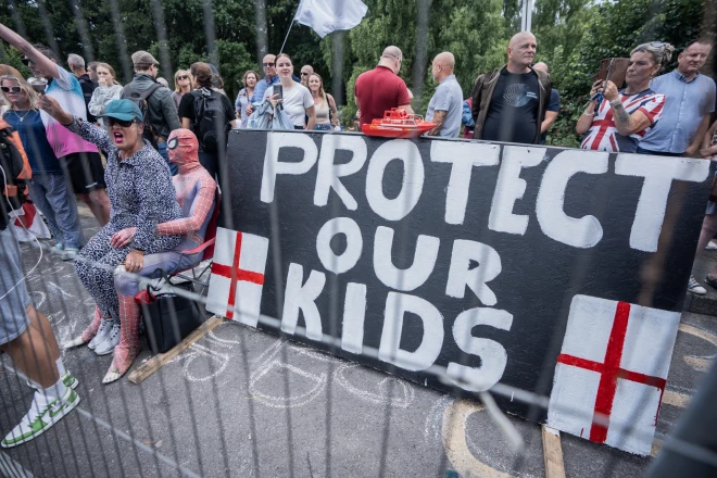 Pret imigrāciju vērstie protestētāji rokās tur plakātu: “Aizsargāsim mūsu bērnus”