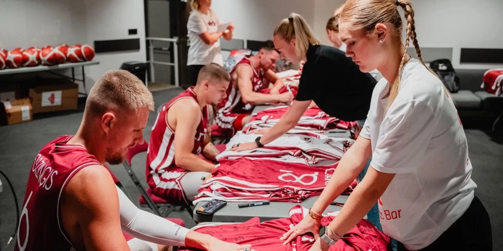 Latvijas basketbolisti liek autogrāfus uz lērums spēļu krekliem. 