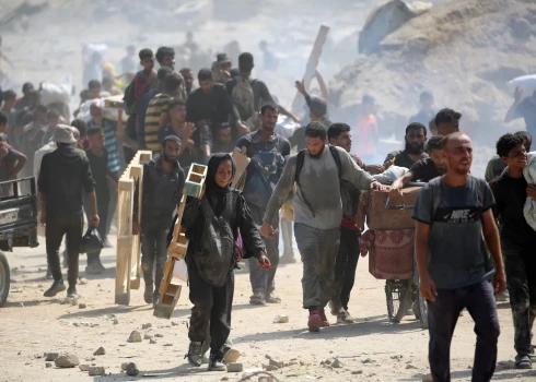 Palestīnieši atgriežas ar maisiem un koka paliktņiem no pārtikas izplatīšanas punkta, ko vada ASV un Izraēlas atbalstītā Gazas Humānās palīdzības fonda (GHF) grupa Gazas joslas centrālajā daļā 2025. gada 2. augustā.