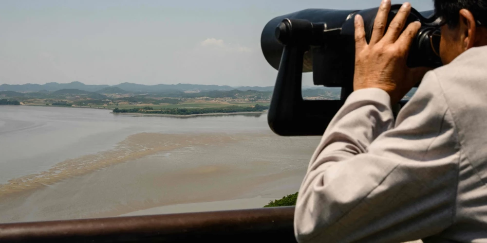 Apmeklētājs, izmantojot binokli, vēro Ziemeļkorejas pusi.