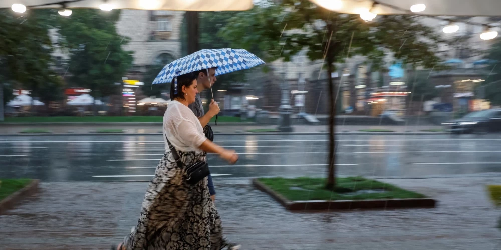 Cilvēki Kijivas centrā spēcīga lietus laikā 2025. gada 6. augustā.
