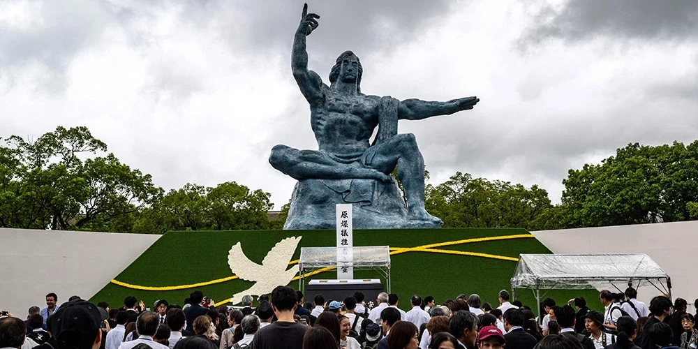 Cilvēki stāv Miera statujas priekšā pēc ikgadējās upuru piemiņas ceremonijas Miera parkā Nagasaki 2025. gada 9. augustā, lai atzīmētu Otrā pasaules kara laikā notikušās atombumbas sprādziena 80. gadadienu.