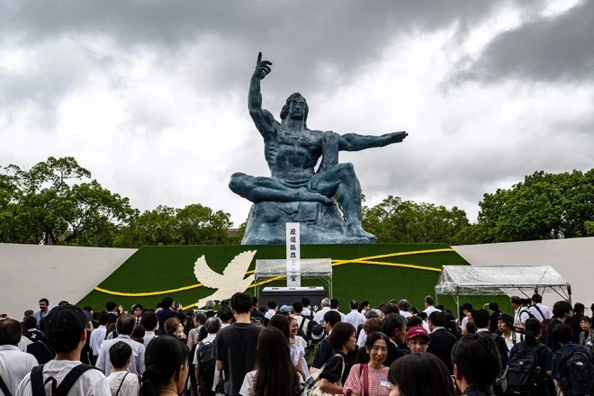 Cilvēki stāv Miera statujas priekšā pēc ikgadējās upuru piemiņas ceremonijas Miera parkā Nagasaki 2025. gada 9. augustā, lai atzīmētu Otrā pasaules kara laikā notikušās atombumbas sprādziena 80. gadadienu.