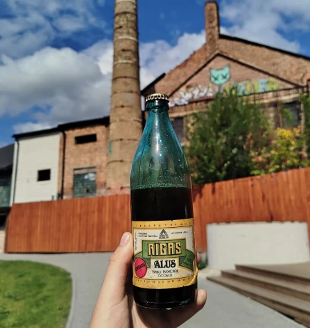 Unikālā 1970. gada ražotā Rīgas miestiņa pudele (fonā – pamestās Rīgas alus fabrikas skurstenis Bruņinieku ielā (padomju okupācijas laikā - Sarkanarmijas iela).