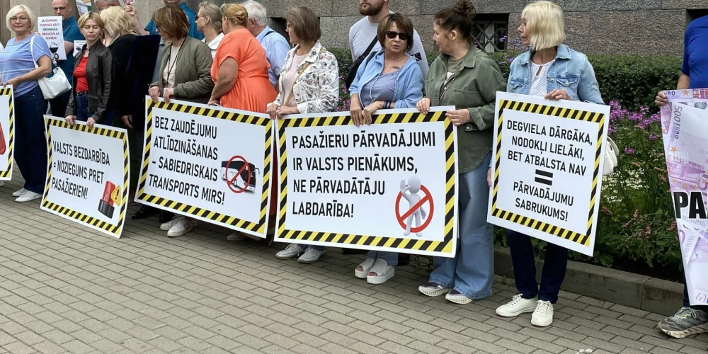 Протестующие держат плакаты, например "Закрытие рейсов ничего не решит!", "Заплатите за работу!", "Цены и зарплаты растут. Кто компенсирует наши убытки?", "Мы ответственны, мы не отнимаем мобильность у тех, для кого общественный транспорт - единственный способ передвижения".