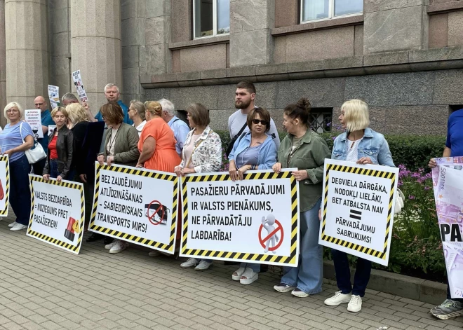 Протестующие держат плакаты, например "Закрытие рейсов ничего не решит!", "Заплатите за работу!", "Цены и зарплаты растут. Кто компенсирует наши убытки?", "Мы ответственны, мы не отнимаем мобильность у тех, для кого общественный транспорт - единственный способ передвижения".