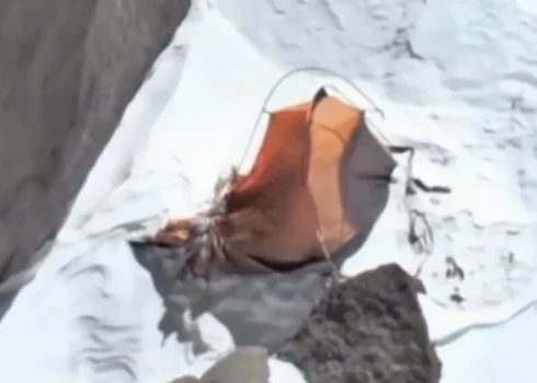 Skats no drona uz alpīnistes telti kalnos.