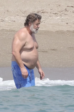 61-летний Кроу освежился, искупавшись в море в голубых плавательных шортах, после чего вернулся на шезлонг, чтобы отдохнуть и закурить сигарету.