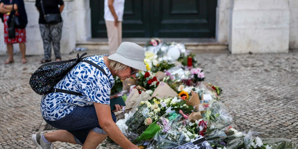 CORRECTION / A woman places flowers next to other tributes displayed at the site of the Gloria funicular accident in Lisbon on September 5, 2025. 16 people were killed and 21 injured in a funicular accident on September 3, 2025. The yellow Gloria funicular veered off a steep stretch of tracks evening in one of Lisbon's most popular tourist spots, crashing into a building. (Photo by PATRICIA DE MELO MOREIRA / AFP) / The erroneous mention appearing in the metadata of this photo by PATRICIA DE MELO MOREIRA has been modified in AFP systems in the following manner: [16 people were killed and 21 injured in a funicular accident on September 3, 2025] instead of [16 people were killed and 21 injured in a funicular accident on September 4, 2025]. Please immediately remove the erroneous mention[s] from all your online services and delete it (them) from your servers. If you have been authorized by AFP to distribute it (them) to third parties, please ensure that the same actions are carried out by them. Failure to promptly comply with these instructions will entail liability on your part for any continued or post notification usage. Therefore we thank you very much for all your attention and prompt action. We are sorry for the inconvenience this notification may cause and remain at your disposal for any further information you may require.