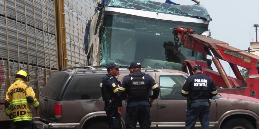 Policisti norobežo satiksmes negadījuma vietu, kur kravas vilciens ietriecās autobusā.