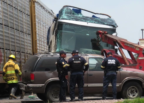 Policisti norobežo satiksmes negadījuma vietu, kur kravas vilciens ietriecās autobusā.