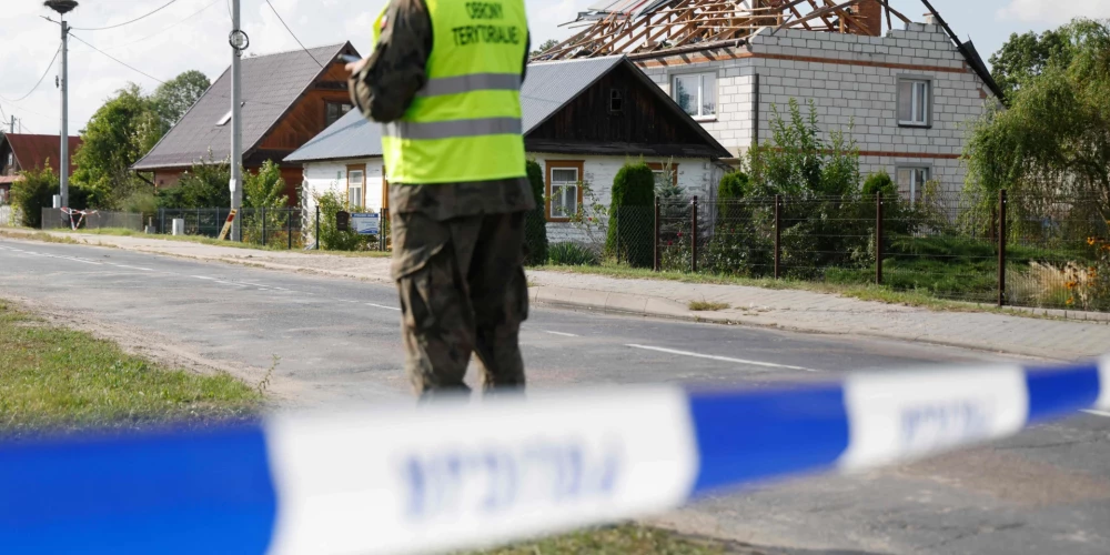 Policija un karavīri pārbauda bojājumus mājai, kas radušies, kad uz tās nokrita Krievijas bezpilota lidaparāta nogāztās atlūzas.