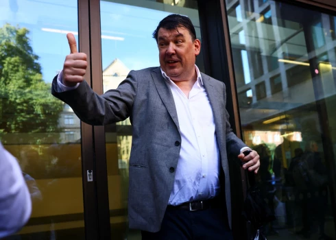 Īru rakstnieku Greiemu Lainenu sauc tiesas priekšā par ieteikumu vīriešiem, kas lien sieviešu ģērbtuvēs un tualetēs, iespert “pa olām”. r Graham Linehan, who has been charged with harassment and criminal damage involving a transgender activist, gestures outside Westminster Magistrates' Court, in London, Britain, September 4, 2025. REUTERS/Jack Taylor