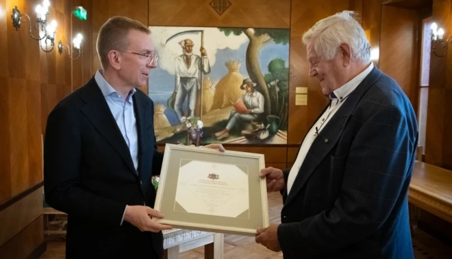 Valsts prezidents Edgars Rinkēvičs pasniedz Cildinājuma rakstu Dainim Kalnam.