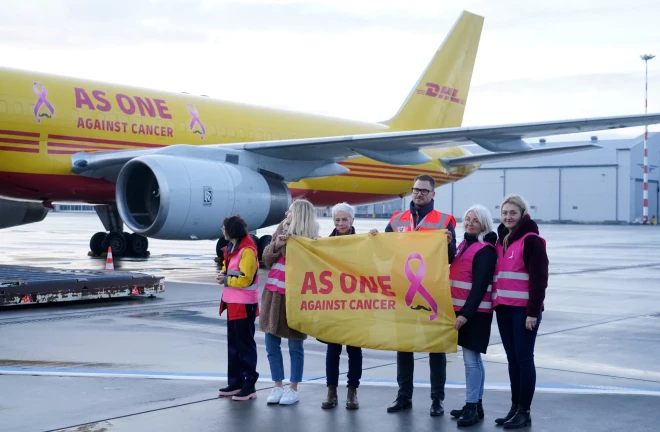 Rīgas lidostā notiek pasākums, kurā sagaida krūts vēža pacientu atbalstīšanai dizainētu loģistikas uzņēmuma "DHL" lidmašīnu.