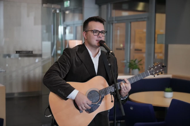 Kamēr Mārtiņš sniedza muzikālo priekšnesumu savas dzejas grāmatas atklāšanā, sieva Žanete viņu vēroja ar mīlestības pilnu skatienu.