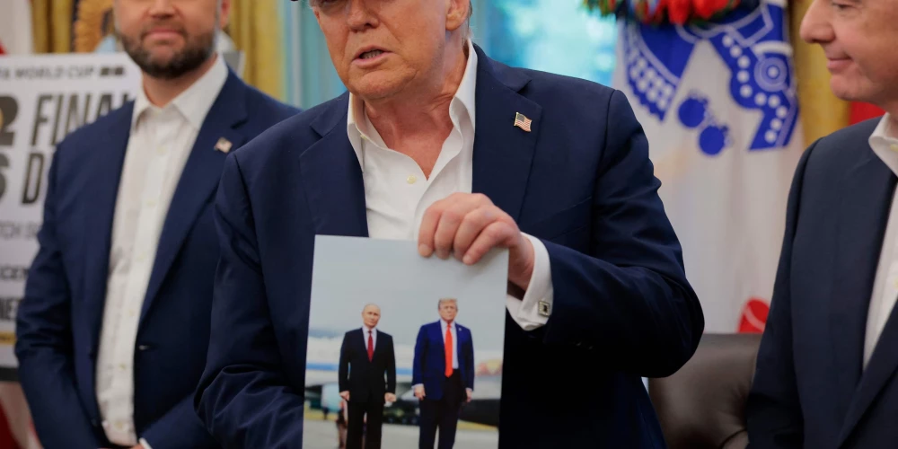 Президент США Дональд Трамп держит фотографию, на которой он запечатлён вместе с президентом России Владимиром Путиным на Аляске, в Овальном кабинете 22 августа 2025 года в Вашингтоне.