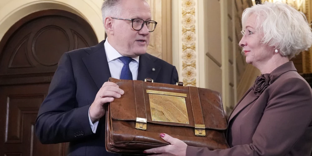 Министр финансов Арвилс Ашераденс передает пакет бюджетных законопроектов председателю Сейма Дайге Миерине.