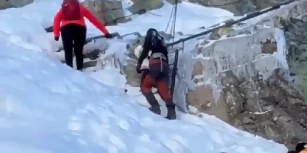 Pārgalvīgie vecāki kāpj kalnā ar zīdaini (ekrānuzņēmums no video)