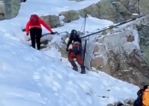 Pārgalvīgie vecāki kāpj kalnā ar zīdaini (ekrānuzņēmums no video)