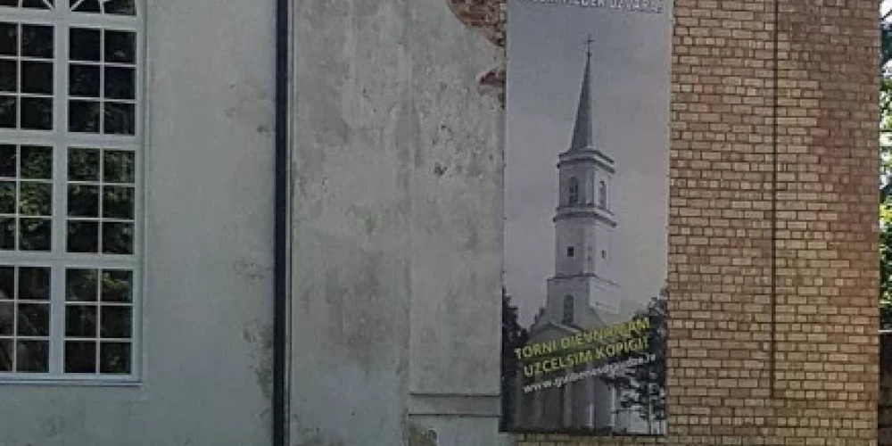 Gulbenes luterāņu baznīca ar plakātu, kurā attēlots baznīcas tornis (foto: lelbgulbenesdraudze.lv)