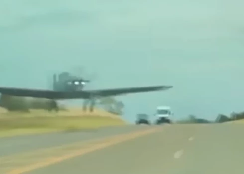 ASV kara lidmašīna par mata tiesu palido garām pretī braucošajai automašīnai (ekrānuzņēmums no video)