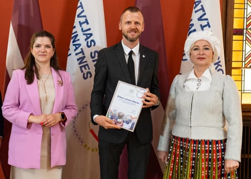 Ķekavas novada kultūras darba vadītājs Ēriks Laime Babris no Saeimas priekšsēdētājas Daigas Mieriņas, saņemot pateicības rakstu par ieguldījumu XIII Latvijas Skolu jaunatnes dziesmu un deju svētku koordinēšanā.