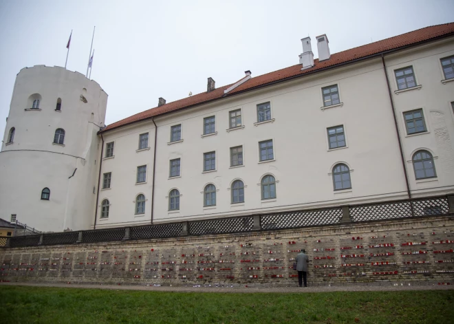 Cilvēki noliek svecītes pie Rīgas pils mūra par godu Lāčplēša dienai.