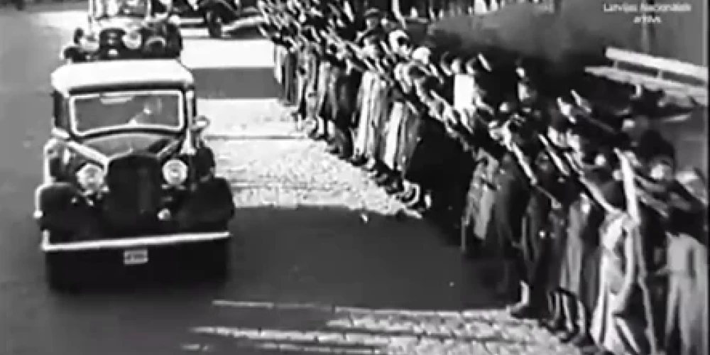 1935. gada 18. novembrī tūkstošiem latviešu Valsts prezidenta un valdības vadītāja kortežu uz Brīvības pieminekļa atklāšanu sveicina ar izstieptu labo roku.