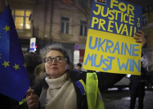 Sieviete tur plakātu ar uzrakstu "Ukrainai ir jāuzvar".