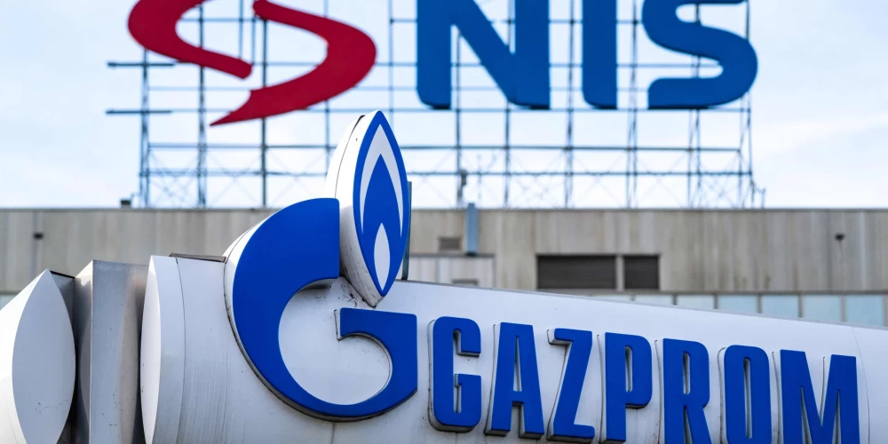 "Naftna Industrija Srbije" (NIS) logotips uz galvenās mītnes Belgradā, bet priekšplānā "Gazprom" gāzes uzpildes stacija