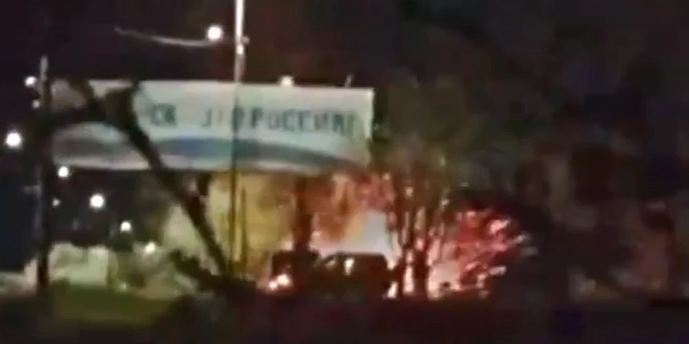 Krievijas karavīru grupa pulcējās zem propagandas reklāmas stenda pie iebraukšanas okupētajā Berdjanskā.