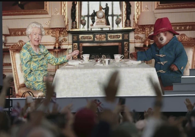 Karaliene Elizabete II un lācēns Padingtons bauda tēju.