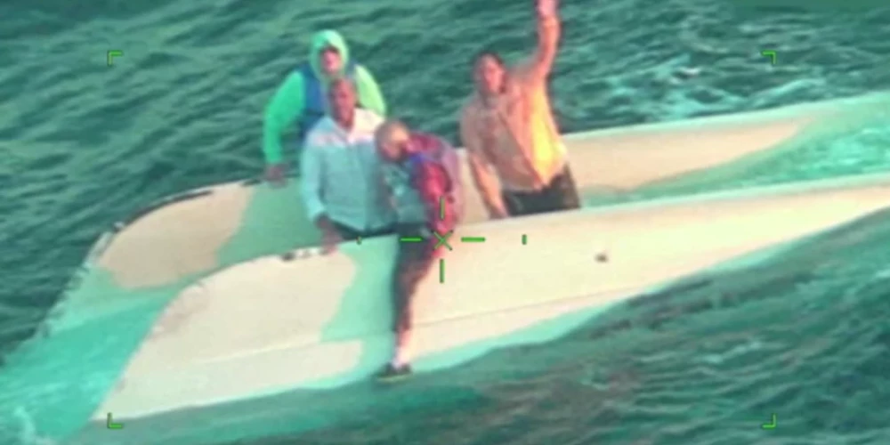 Četri vīrieši uz apgāztā katamarāna sagaida glābējus (ekrānuzņēmums no video)