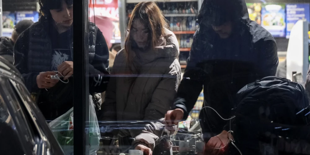 Iedzīvotāji uzlādē savas ierīces veikalā elektroapgādes pārtraukuma laikā pēc tam, kad Krievijas raķešu un dronu uzbrukumos tika skarta kritiskā civilā infrastruktūra. Odesa, Ukraina, 2025. gada 13. decembris.