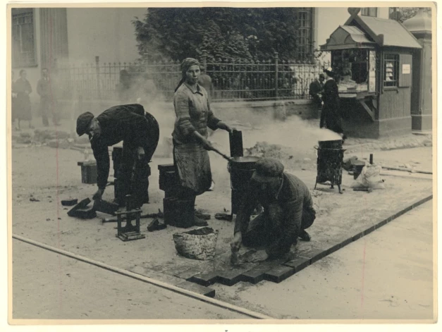 На снимке запечатлен процесс обновления дорожного покрытия на улице Бривибас в межвоенный период: на переднем плане выделены рабочие и сам ход работ. На заднем плане — православный собор Святого Александра Невского и газетный киоск (автор фото неизвестен, 1936 год).