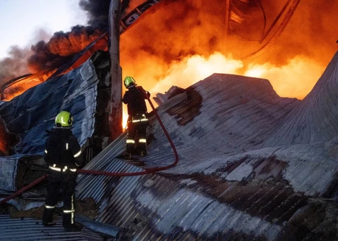 Ugunsdzēsēji Odesā dzēš liesmas sadzīves tehnikas noliktavā, kam naktī uzbrucis Krievijas bezpilota lidaparāts. 2025. gada 16. decembris.