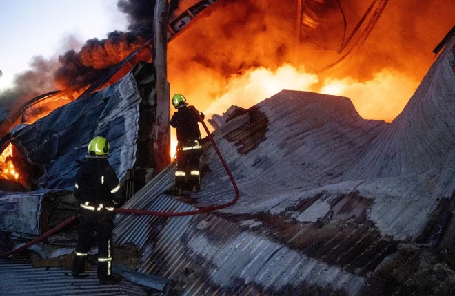 Ugunsdzēsēji Odesā dzēš liesmas sadzīves tehnikas noliktavā, kam naktī uzbrucis Krievijas bezpilota lidaparāts. 2025. gada 16. decembris.