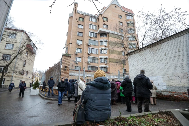 Люди стоят рядом с жилым домом, где расположена квартира певицы Ларисы Долиной в Хамовниках, ставшая предметом недавнего резонансного судебного процесса по делу о мошенничестве высокого профиля.