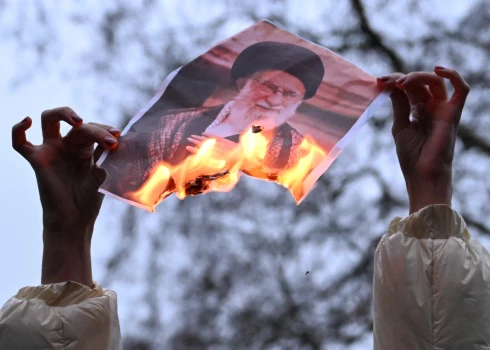 Lēnām deg fotogrāfija, kur redzams Irānas augstākais līderis Ali Hamenei.