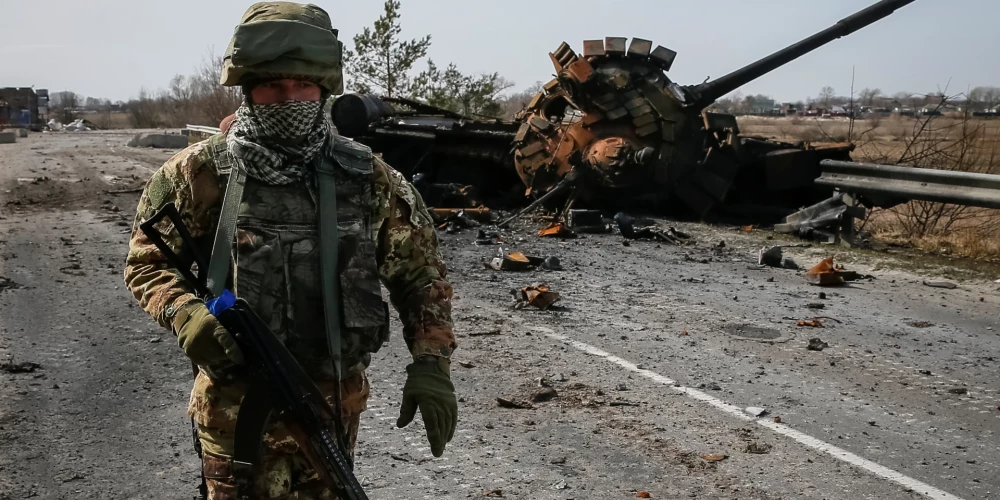 Ukrainas karavīrs iet garām iznīcinātam Krievijas tankam Kijivas apgabalā. 2022. gada 28. marts.