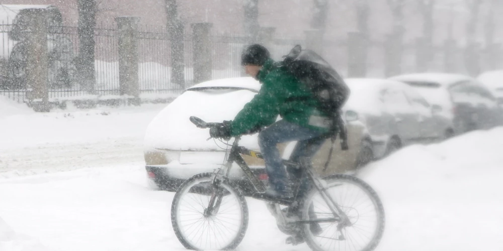 Riteņbraucējs uz ielas puteņa laikā.