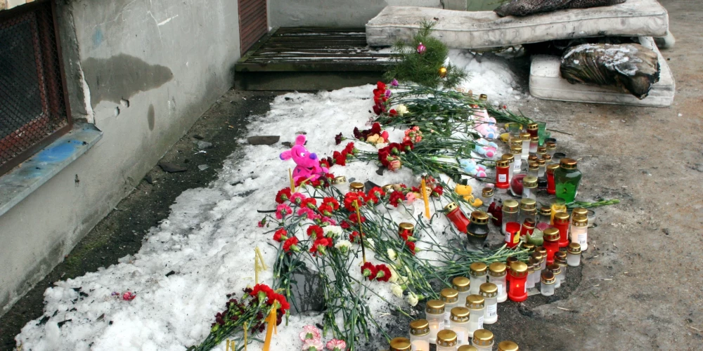 Ziedi un svecītes vietā, kur 2006. gada 6. janvāra ugunsgrēkā pa astotā stāva logu Mirdzas Ķempes ielā izlēca abi vecāki un trīs bērni
