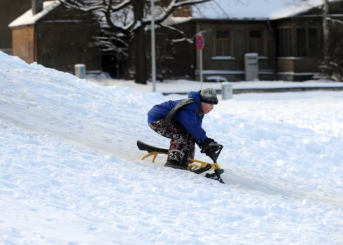 Bērni šļūc ar ragavām no kalniņa Uzvaras parkā.