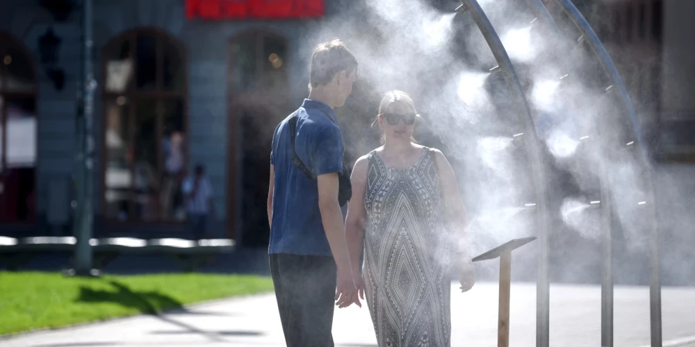 Cilvēki pie ūdens smidzinātājiem Līvu laukumā.