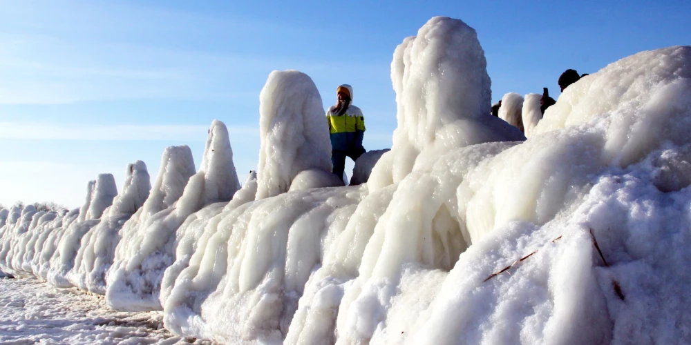 Cilvēki pie apledojuša Engures mola ziemā.