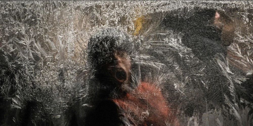 Jaunietis 15. janvārī Kijivā ar elpu cenšas atkausēt aizsalušo autobusa logu. 