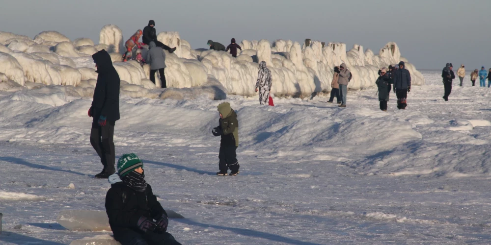 Cilvēki pie apledojuša Engures mola ziemā.